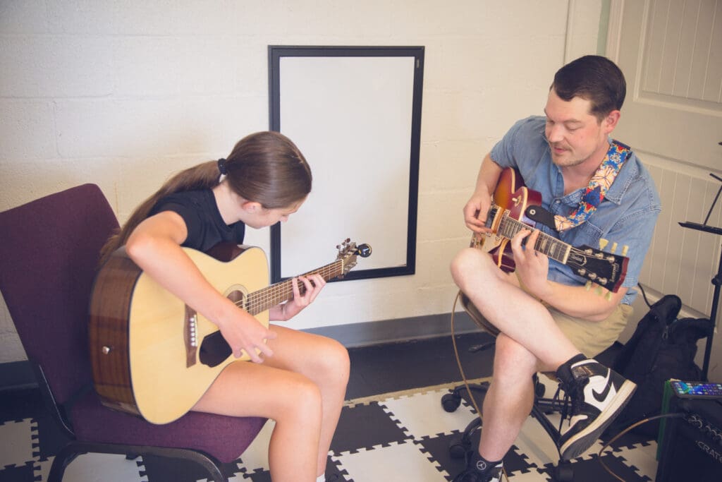 Guitar teacher working with a student during a private lesson
